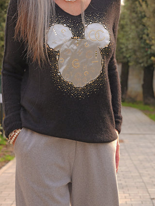 OFF#DLY Pulli Kira black: Schwarzer Pullover mit lockerem Schnitt, verziert mit metallischen Nieten und appliziertem Mäusekopf-Motiv, kombiniert mit grauen Hosen. Armbänder und Goldkette als Accessoires.