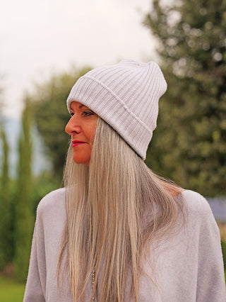 Frau im Profil mit silbergrauem Haar trägt die OFF#DLY Mütze Anna eisgrau, eine gerippte Strickmütze. Sie ist lässig gekleidet mit einem hellen Oberteil.
