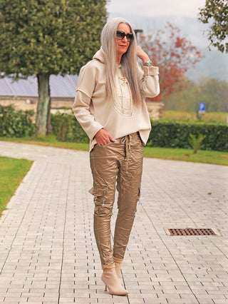 Eine stilvolle Frau trägt die OFF#DLY Jacke Alina beige, ein oversized Teddy-Look Hoodie mit zartem Strukturmuster, das lässig-modern wirkt. Die Jacke ergänzt perfekt ihre elegante Outdoor-Garderobe.