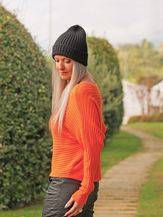 Die Frau trägt den OFF#DLY Pulli Cara orange, einen modernen, gerippten, leicht verkürzten, orangefarbenen Pullover mit weichem Material, perfekt für einen gemütlichen und stilvollen Look.