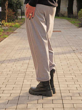 Person trägt OFF#DLY Hose Ronja grau mit grauem Fischgrätmuster, locker sitzend, umgeschlagene Bündchen. Kombiniert mit klobigen schwarzen Schnürstiefeln. Eine Hand mit Ringen und dunklem Nagellack sichtbar.