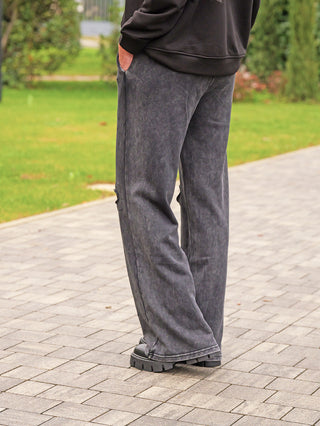 OFF#DLY Joggingpant Glitzer Destroy black: Weit geschnittene Jogginghose mit glitzernden Details und Destroy-Effekten an den Knien, getragen mit schwarzen klobigen Schuhen auf einem gepflasterten Weg.