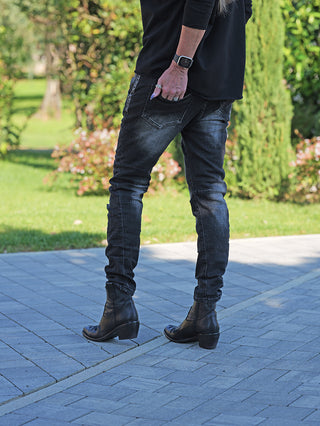 OFF#DLY Denim Julia Black Wash: Schlanke, dunkel gewaschene Jeans mit Destroy-Details, getragen mit schwarzen Lederstiefeletten. Hand mit Ringen und Uhr ruht lässig in Hosennähe.