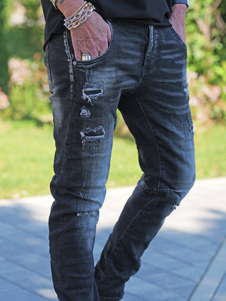 Nahaufnahme von OFF#DLY Denim Julia Black Wash Jeans mit Destroy-Details, getragen mit Metallarmbändern und Ring. Slim-Fit-Schnitt mit modernem Black-Wash-Finish und Stretch für Komfort.