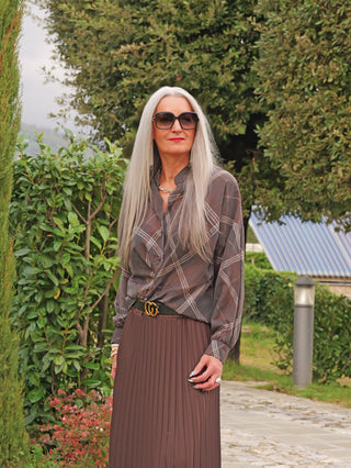 Die OFF#DLY Bluse Tanja asphalt/mix wird von einer Frau mit silbernem Haar getragen, mit semi-transparentem, grafisch gemustertem Stoff, der in einen hoch taillierten Rock gesteckt ist.