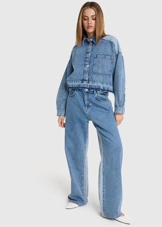 Model trägt die ALIX Denim Blouse light blue Denim, eine kurz geschnittene, zweifarbige Jeansjacke mit Brusttasche und ausgefranstem Saum, kombiniert mit passenden zweifarbigen Jeans und weißen Schuhen.