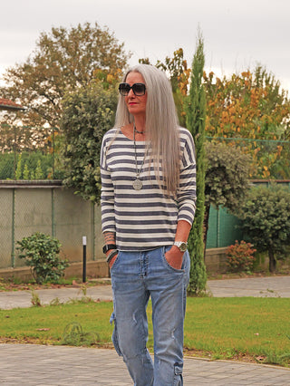 OFF#DLY Ringel Glitzer Delia marine: Person mit gestreiftem, glitzerndem Langarmshirt in lockerer Passform, kombiniert mit lässigen Cargo-Jeans, im Garten stehend.