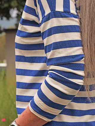 OFF#DLY Ringel Glitzer Delia royalblue: Oberkörper mit langärmligem Ringelshirt in Blau-Creme, feiner Glanz durch Lurexfaden, sichtbar am Ärmel mit Uhr, ergänzt durch langes Haar.