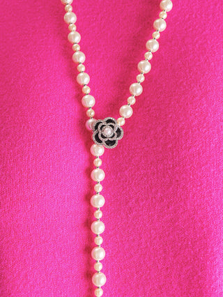 OFF#DLY Kette Rose black/silver: Y-förmige Kunstperlenkette mit verstellbarem Rosen-Clip in Schwarz und Silber, zentriert mit einer kleinen Perle, auf farbigem Hintergrund präsentiert.