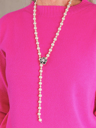 OFF#DLY Kette Rose black/silver: Lariat-Kunstperlenkette mit verstellbarem Blumen-Clip in Schwarz/Silber, getragen über einem pinken Strickpullover.