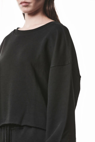 Thom Krom WS496 Sweat black: Locker geschnittener, schwarzer Cropped-Sweater mit überschnittenen Schultern, geripptem Rundhalsausschnitt und offenen Kanten für einen minimalistischen, avantgardistischen Look. Gesicht teils sichtbar.