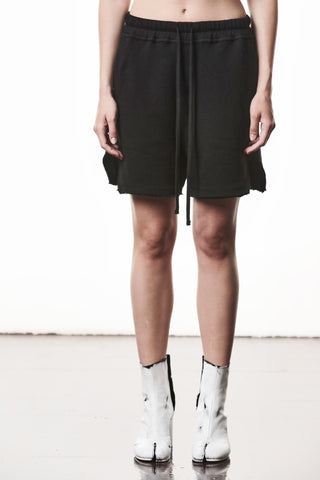 Thom Krom WST 432 Hose black: Locker geschnittene, schwarze Baumwoll-Shorts mit elastischem Bund und Bindeband, fransigen Saumkanten und seitlichen Taschen, getragen mit markanten weißen Boots mit geteilten Zehen.