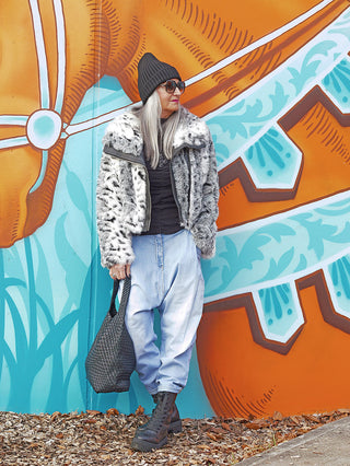 Person vor farbenfrohem Wandbild trägt OFF#DLY Denim Hella lightblue. Die locker sitzende, moderne Jeans aus 100 % Baumwolle ergänzt urbanen Look mit lässiger Eleganz.