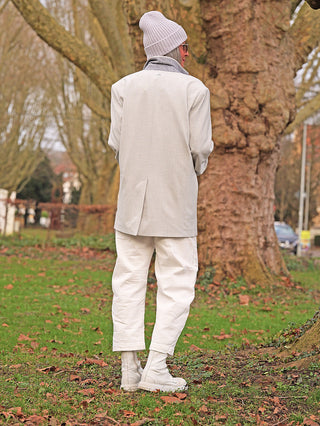 Person in hellem Winteroutfit steht draußen. Sie trägt die OFF#DLY White Denim Nina, eine gerade geschnittene Hose, die Komfort und stilvollen Look vereint, ideal für vielseitige Styles.