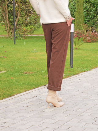OFF#DLY Hose Ronja coffee: Eine Person trägt braune, locker sitzende, umgeschlagene Hose. Kombiniert mit beigefarbenen Stiefeletten, bietet sie modernen Stil und Komfort.