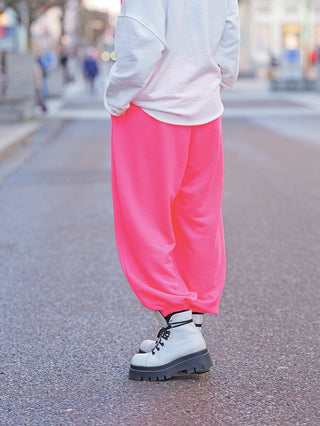 Die OFF#DLY Sweatpant Pinky pink zeigt sich in leuchtendem Pink mit lockerem Schnitt, elastischem Bund und Bündchen. Die joggerartigen Hosen sind in weiße, klobige Schnürstiefel gesteckt.