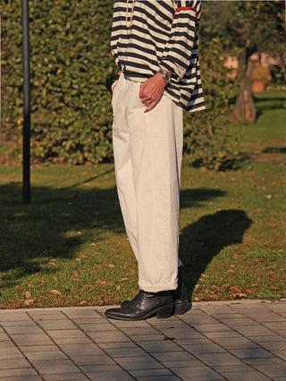 Person trägt die OFF#DLY Joggpant Melania creme mit lässig-geradem Schnitt, seitlichen Eingrifftaschen und umgeschlagenen Beinabschlüssen. Kombiniert mit Streifenshirt und schwarzen Stiefeletten.