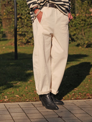 Person in OFF#DLY Joggpant Melania creme, locker gerollt an den Knöcheln, kombiniert mit schwarzen Cowboy-Stiefeln. Dezente Details und lässiger Schnitt für eleganten Komfort sichtbar.