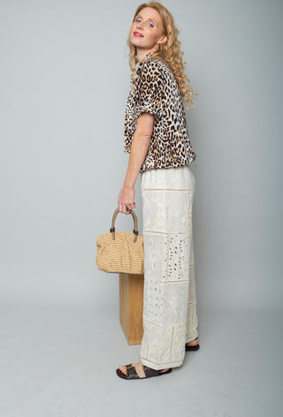 Emily Bluse 157990 leo präsentiert sich in einem lässigen Leopardenmuster, kurzärmelig mit Knopfleiste und elastischem Saum. Kombiniert mit High-Waist-Hosen und Strohtasche für einen stilvollen Look.