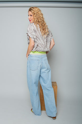 Die Emily Bluse 158240 taupe zeigt sich im lockeren Zebra-Print, mit schmaler Ärmelsaumblende und neongelbem Strickbündchen, kombiniert mit hochgeschnittener, weitbeiniger Jeans.