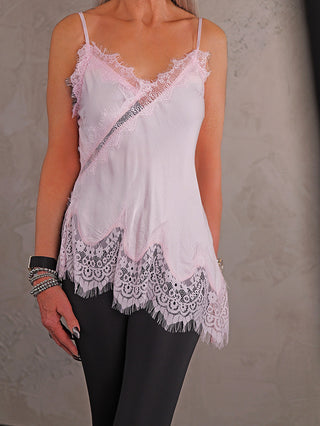 Person trägt das OFF#DLY Top Violetta rose mit Spitzenverzierung an Ausschnitt und Saum, kombiniert mit schwarzen Leggings und mehreren Armbändern am linken Handgelenk.