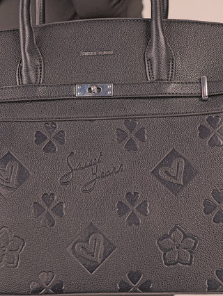 Nahaufnahme der Sweet Years Shopper 6929 black Handtasche mit eingeprägtem Kleeblatt-, Blumen- und Herzmotiv, Sweet Years Logo, silbernem Drehverschluss und zwei Ledergriffen.