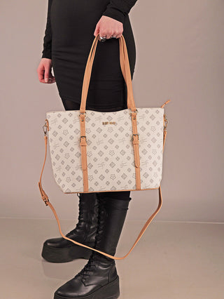 Person hält die Sweet Years Shopper 71 Tasche mit grauem Emblem-Muster und braunen Ledergriffen, dazu ein abnehmbarer Schulterriemen. Sie trägt einen schwarzen Kleid und Schnürstiefel.