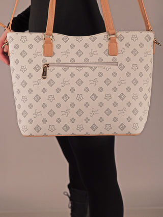 Sweet Years Shopper 71: Cremefarbene Tasche mit Blumenmuster, tanfarbenen Lederdetails und Front-Reißverschlusstasche, gehalten von einer Person in Schwarz. Ideal für Alltag und Shopping.