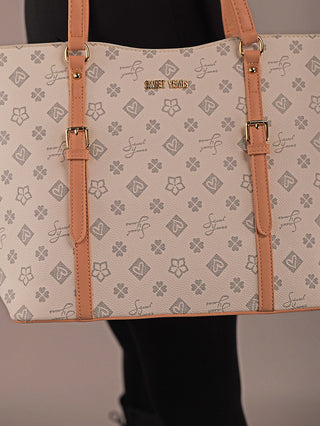 Die Sweet Years Shopper 71 Tasche zeigt ein beige-graues Muster mit Blumen- und S-Symbolen, hat tanfarbene Ledergriffe und eine goldene SWEET YEARS Plakette, gehalten von einer dunkel gekleideten Person.