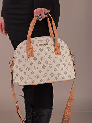 Nahaufnahme einer Person mit der Sweet Years Bag 68 grey, einer kuppelartigen Off-White-Tasche mit grauem Blumenmuster, goldener SWEET YEARS-Prägung, tanfarbenen Ledergriffen und passendem Schultergurt.