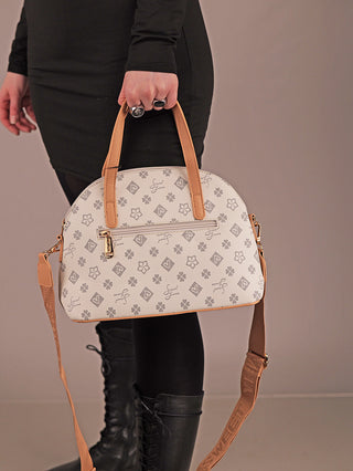 Die Sweet Years Bag 68 grey ist eine strukturierte, kuppelförmige Handtasche mit floralen Mustern, tanfarbenen Ledergriffen und goldenen Details, die von einer Person in schwarzer Kleidung gehalten wird.