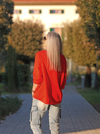 Person von hinten auf Baumallee trägt das OFF#DLY Longsleeve Brklyn red, ein locker geschnittenes rotes Oberteil mit hochgekrempelten Ärmeln, ideal für einen lässigen, urbanen Stil.