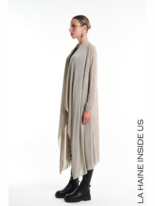 Seitliches Studiofoto eines Models im La Haine Cardigan W5324 Fango, einem langen, fließenden, offenen Cardigan in Beige/Taupe, kombiniert mit schwarzen Unterteilen und klobigen, schwarzen Lederstiefeletten.