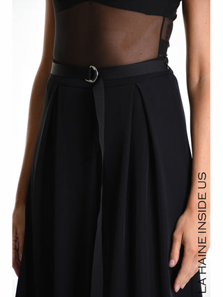 Frau trägt La Haine Bermuda LW5322 black, eine weite, fließende Bermuda mit Bügelfalten und elastischem Bund, kombiniert mit einem transparenten schwarzen Mesh-Top und einem schmalen Gürtel.