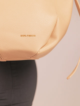 Regina Schrecker Tasche 5020 sand, eine elegante, beige pebbled-leather Handtasche mit dünnem Schulterriemen und goldener Prägung, bietet zeitloses Design und Funktionalität, ideal für Alltag und Abend.