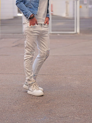 OFF#DLY Denim White Flowers: Slim-fit Jeans mit dezenten floralen Stoffeinsätzen und leichten Distressed-Details, kombiniert mit chunky Sneakern. Perfekt für einen modernen, urbanen Look.