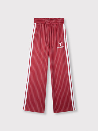 ALIX Pinstripe Trainingpant Cerise mit vertikalen weißen Nadelstreifen, doppelte Seitenstreifen, elastischem Bund mit Kordelzug, Bull-Stickerei und „THE LABEL“-Schriftzug, bietet sportlichen Stil und Komfort.