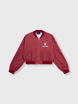 ALIX Pinstripe Trainingsjacke cerise mit burgundy-weißem Nadelstreifenmuster, kurzem Schnitt, silbernem Frontreißverschluss, zwei Taschen, gerippten Bündchen und markanter Bull-Stickerei mit „THE LABEL“-Schriftzug auf der Brust.