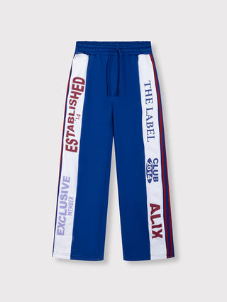 ALIX Logo Tape Pant royal blue: Blaue Track-Style-Sweatpants mit weißen Seitenpanelen, roten und blauen Slogans, elastischem Bund mit Kordelzug und zwei Fronttaschen, modern und sportlich durch markante ALIX-Artworks.