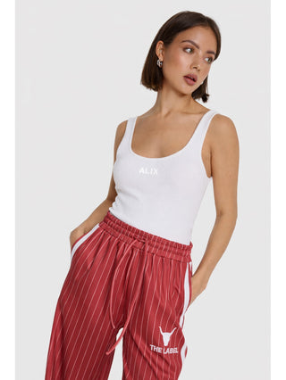 ALIX Rib Tank Top white, getragen von einer jungen Frau. Das Tanktop hat eine körpernahe Passform, geripptes Design und das ALIX-Logo auf der Brust. Perfekt kombinierbar für vielseitige Looks.