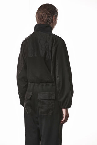 Rückansicht der Thom Krom Jacke WSJ 497 black mit hohem Stehkragen, leicht oversized Schnitt und langen Ärmeln, getragen von einem Modell mit zurückgekämmtem Haar vor weißem Hintergrund.