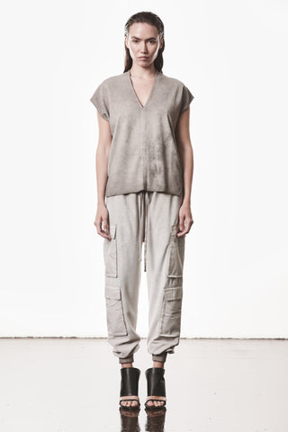 Model trägt Thom Krom Hose WST 427 stone, leicht tiefer Schritt, schmal zulaufendes Bein, aufgesetzte Cargo-Taschen, elastischer Bund mit Tunnelzug, urbaner Avantgarde-Stil.