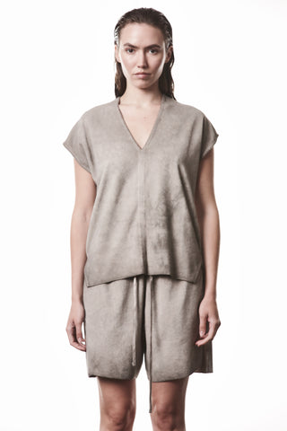 Frau trägt Thom Krom Tee WTS 610 stone, ein lockeres V-Ausschnitt-Oberteil aus weichem Terry-Material, kombiniert mit passenden Shorts, betont durch individuelle Cold-Dye-Waschung und seitliche Schlitze.