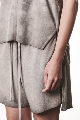 Nahaufnahme des mittleren Bereichs einer Person in einem grauen Terry-Stoff-Set, das Thom Krom Tee WTS 610 stone zeigt. Sichtbar sind die Kordelzug-Shorts und der Saum des passenden Oberteils.
