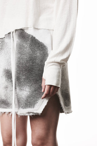 Thom Krom Tee WTS 613 offwhite: Lässig geschnittenes Shirt mit Bootsausschnitt, langen Ärmeln und Daumenlöchern, getragen über einem fransigen Skort mit grauem Spray-Effekt.