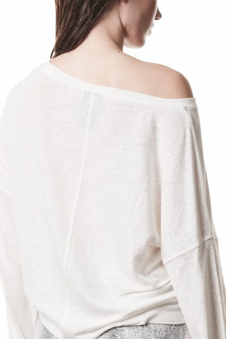 Thom Krom Tee WTS 613 offwhite, von hinten gesehen: lockeres, schulterfreies Oberteil mit Bootsausschnitt, rutscht über eine Schulter, kombiniert mit einem grauen Unterteil, betont moderne Lässigkeit und fließende Silhouette.