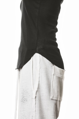 Thom Krom Top black: Seitenansicht eines minimalistischen, ärmellosen Tops mit geschwungenem Saum, sichtbar über hellen Drawstring-Sweatpants. Destroy-Details an Kragen und Armausschnitten betonen den urbanen Look.