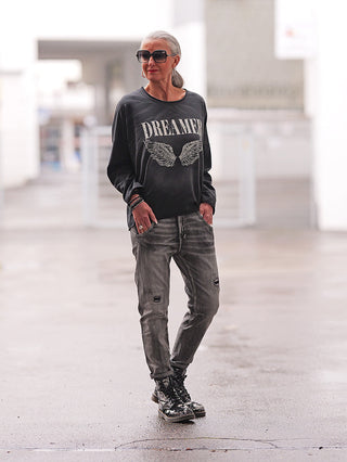 Person trägt OFF#DLY Denim Siena black/grey, graue Used-Waschung, leicht zerstört, kombiniert mit glänzenden Stiefeln und schwarzem Shirt. Jeans betont urbanen Stil und lockeren Schnitt.