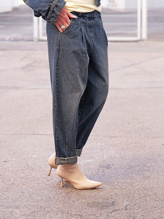 OFF#DLY Denim Jogger darkwash: Dunkel gewaschene, locker sitzende Denim-Hose mit elastischem Bund und umgeschlagenen Säumen, kombiniert mit spitzen Stiefeletten. Hand in der Tasche zeigt silberne Ringe.