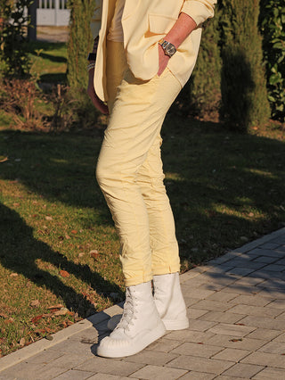 OFF#DLY Joggpant Vera yellow: Slim-fit Hose aus weichem Stoff, kombiniert mit passendem Blazer und weißen High-Top-Sneakern, ideal für einen stilvollen, lässigen Look.